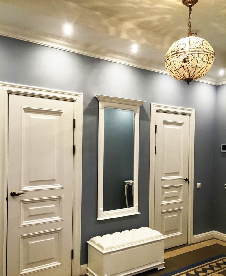 Прихожая изготовлена в одном стиле с квартирой, белый высокие двери, плинтуса в тот же цвет, темные обои под покраску и центральное украшение помещения - это зеркало с пуфиком. Дизайн проект ЖК Саларьево Парк, планировка.