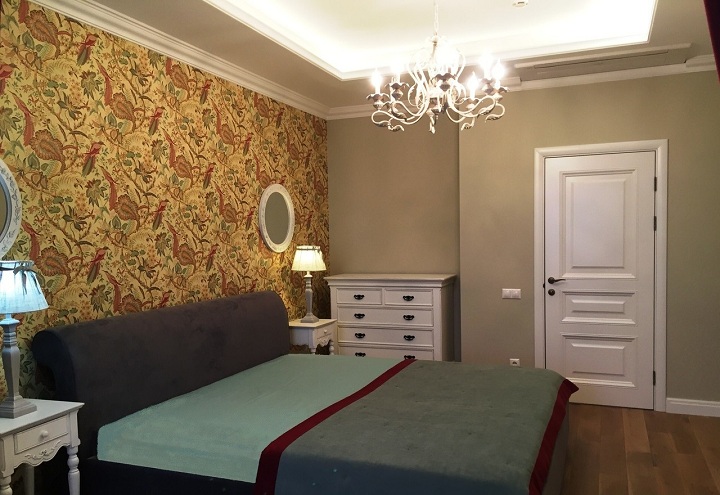 В спальне продолжается общий дизайн интерьера. Обои за спинкой кровати в не крупный цветочек, а по стенам однотонные обои под покраску с немного зеленовато сером цветом.