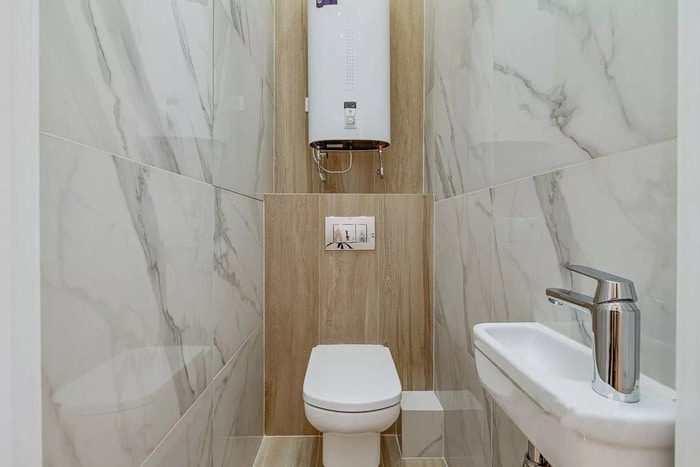Современный туалет с отделкой белым мрамором и плиткой под ламинат.