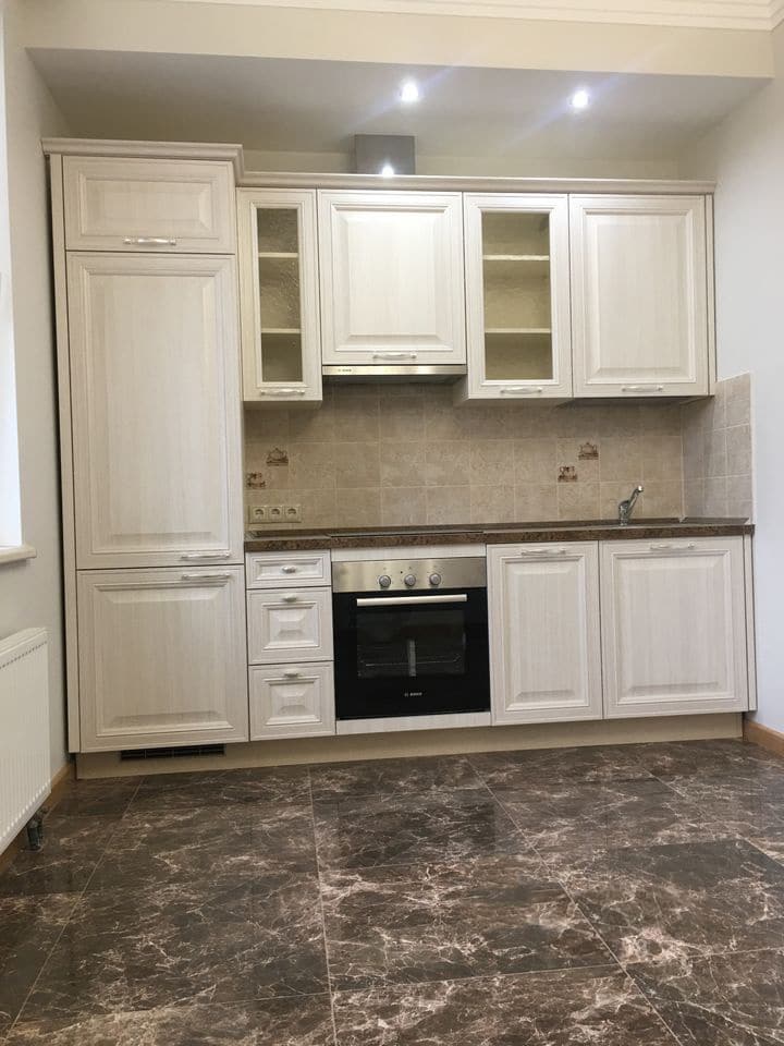 светлая кухня с встроенными и навесными шкафами белого цвета в сочетании с темным мраморным полом